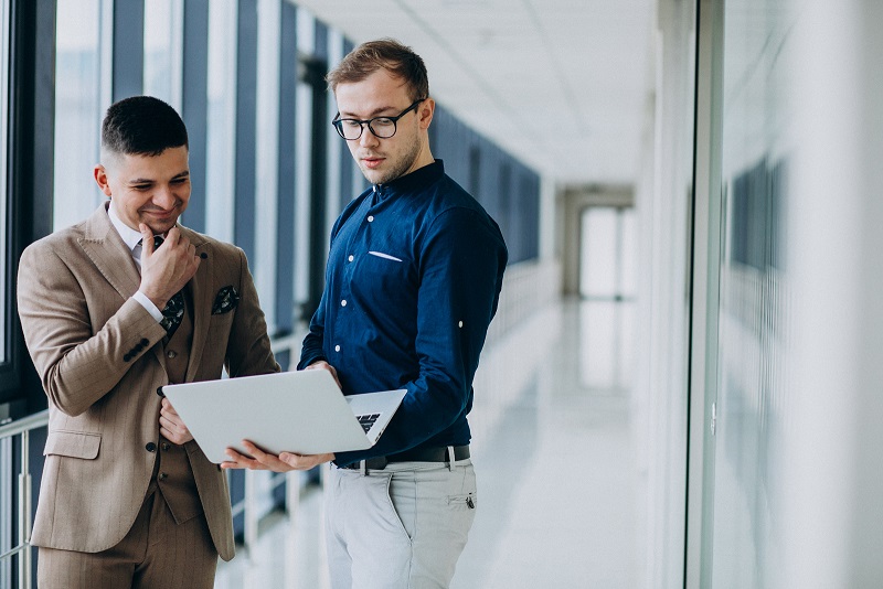 two-male-colleagues-office-standing-with-laptop.jpg